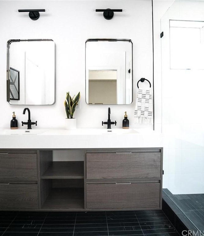 Contemporary bathroom with a black faucet, gray cabinets, and rectangular mirrors.