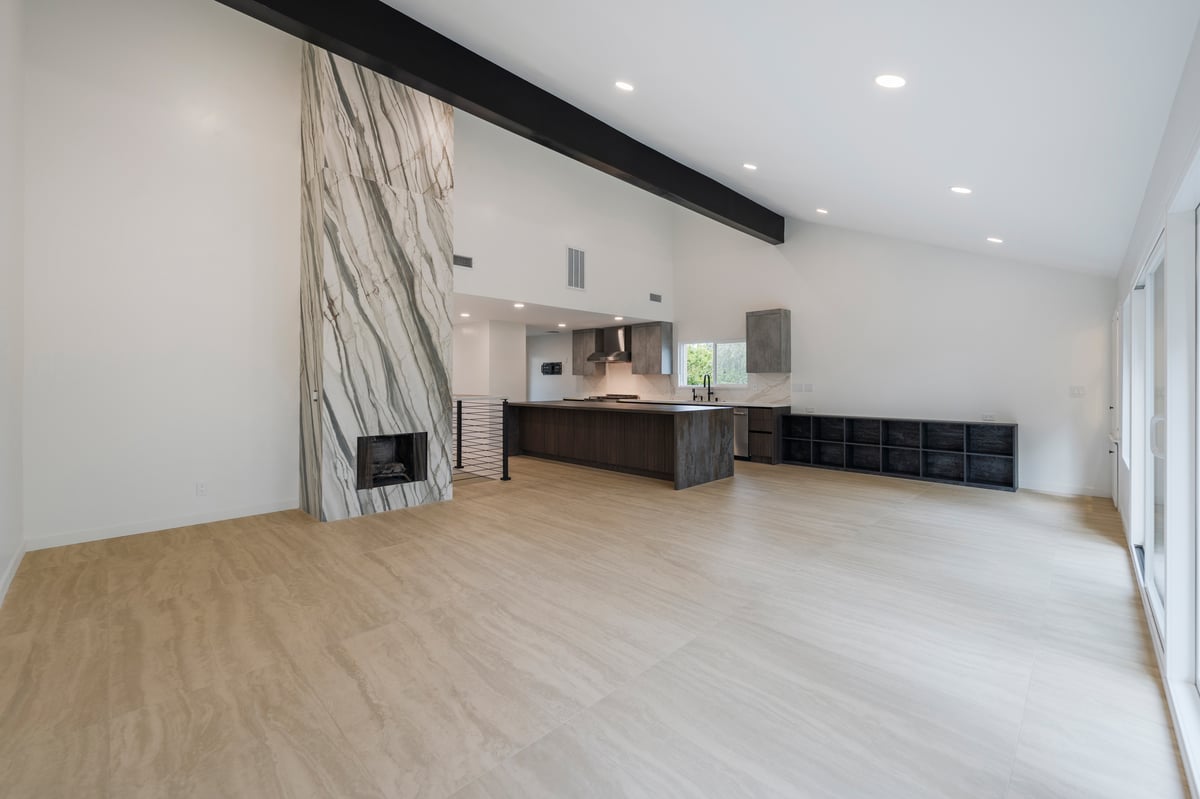 Wide view of living space, exposed wood beam, and custom porcelain fireplace