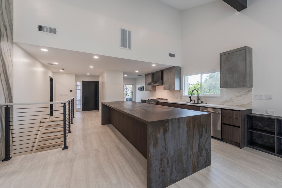 Wide view of modern kitchen with Dekton waterfall island and two-tone cabinetry