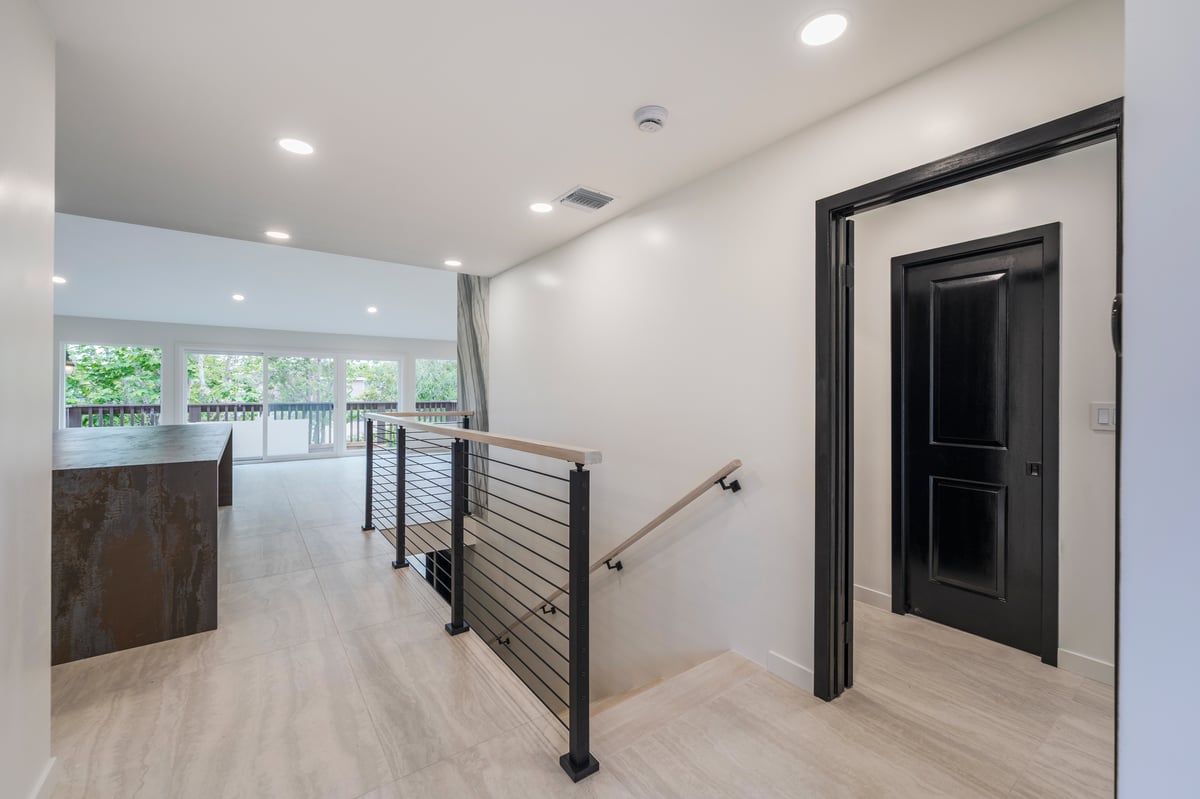 View from front door of staircase with cable railing and dekton countertop