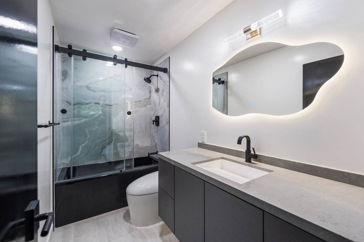 Compact guest bath featuring barn door shower glass and modern porcelain tile