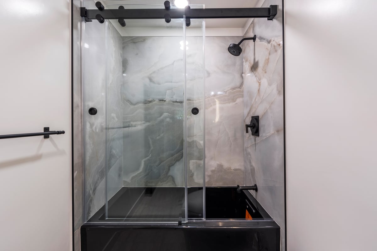 Glass barn door shower glass and modern tilework.