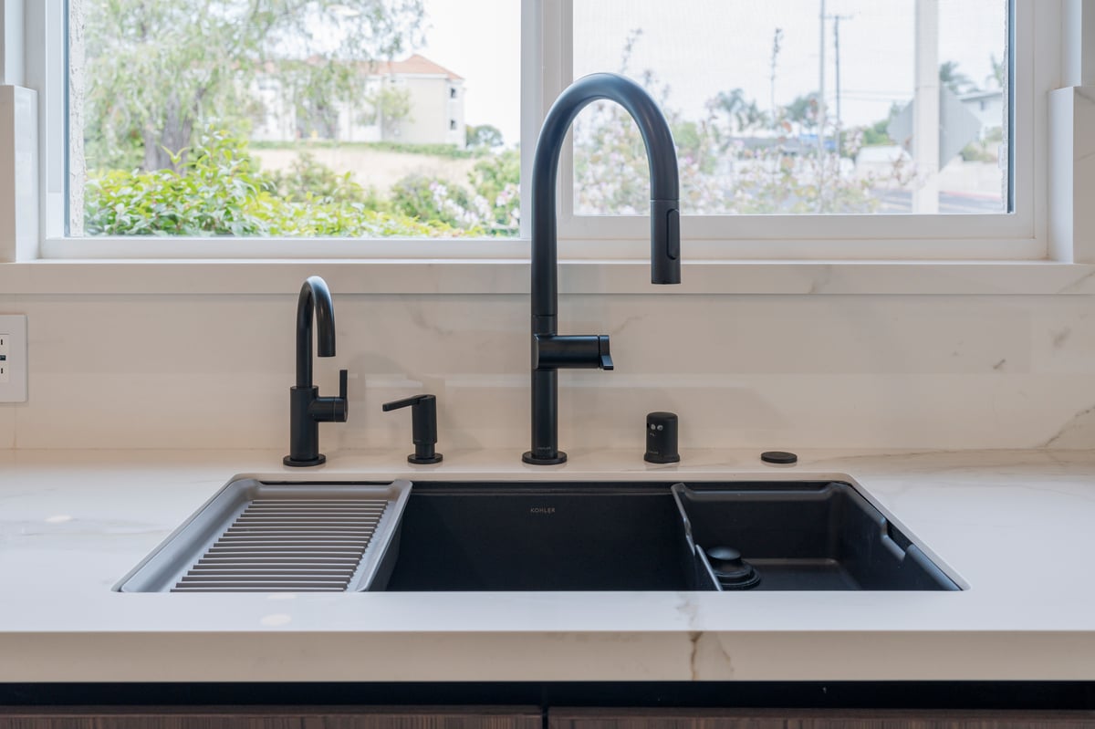 Close up of workstation sink with black fixtures